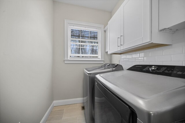 laundry room with washing machine and clothes dryer, cabinet space, and baseboards