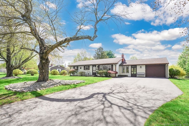 ranch-style house with a garage, a chimney, a front lawn, and aphalt driveway