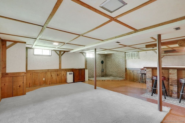 below grade area with visible vents, carpet, a wainscoted wall, and wooden walls