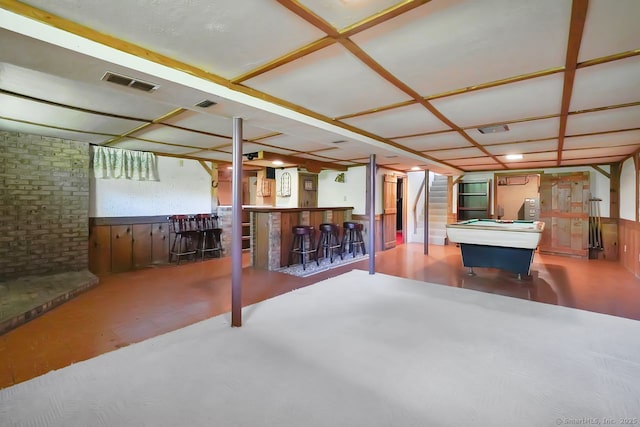 finished basement featuring pool table, a dry bar, brick wall, and visible vents