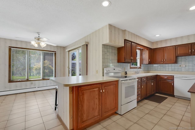 kitchen featuring a sink, light countertops, a baseboard radiator, a peninsula, and white appliances