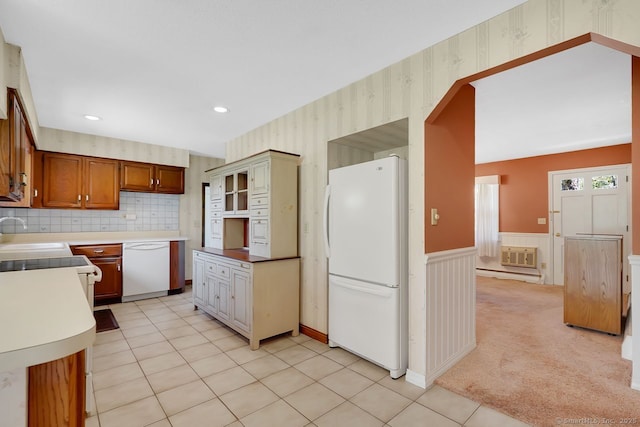 kitchen with wainscoting, white appliances, wallpapered walls, light countertops, and a sink