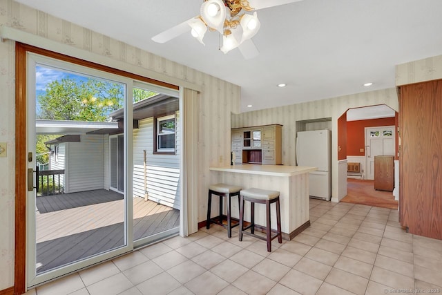 kitchen featuring plenty of natural light, freestanding refrigerator, a peninsula, and wallpapered walls