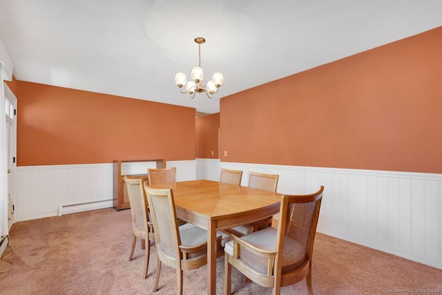dining room featuring an inviting chandelier, a baseboard radiator, light carpet, and wainscoting