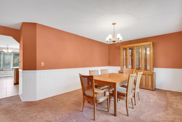 carpeted dining room featuring wainscoting, a baseboard heating unit, and a notable chandelier