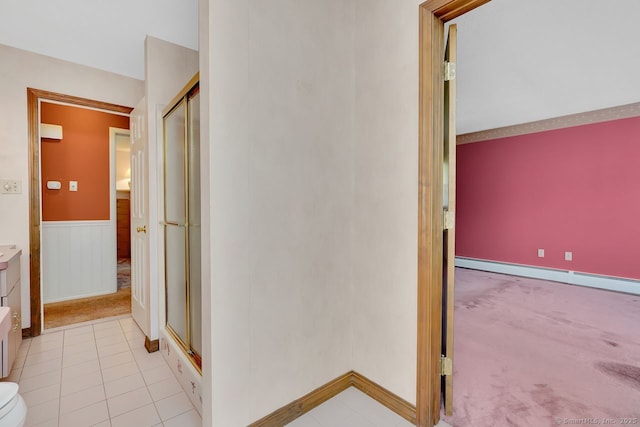 hallway featuring a wainscoted wall, baseboard heating, and light colored carpet
