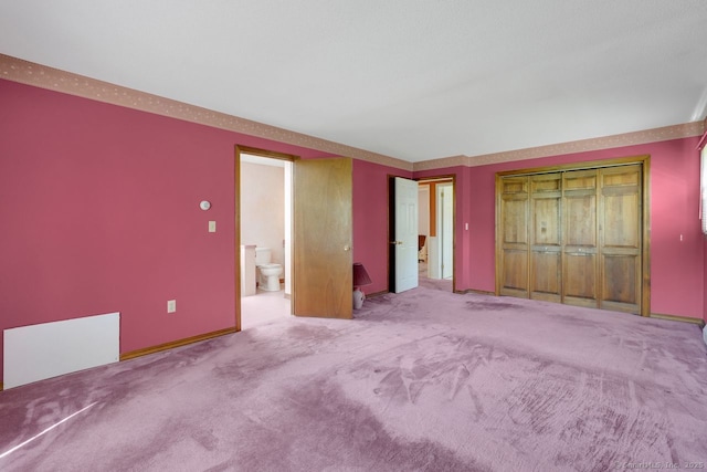 unfurnished bedroom with ensuite bathroom and carpet flooring