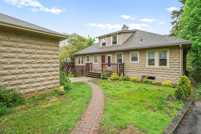 rear view of house featuring a chimney, a deck, a lawn, and a shingled roof