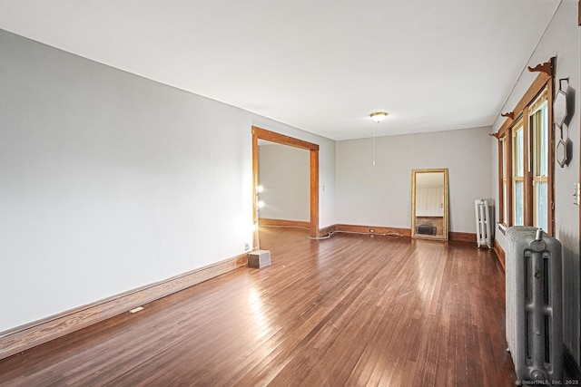 unfurnished room featuring radiator heating unit, hardwood / wood-style flooring, and baseboards