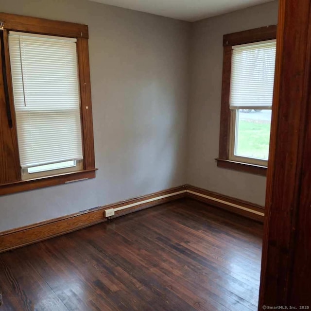 unfurnished room with dark wood-style floors and baseboards