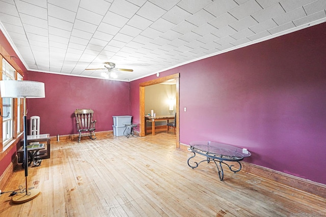 living area featuring wood-type flooring, a ceiling fan, and crown molding