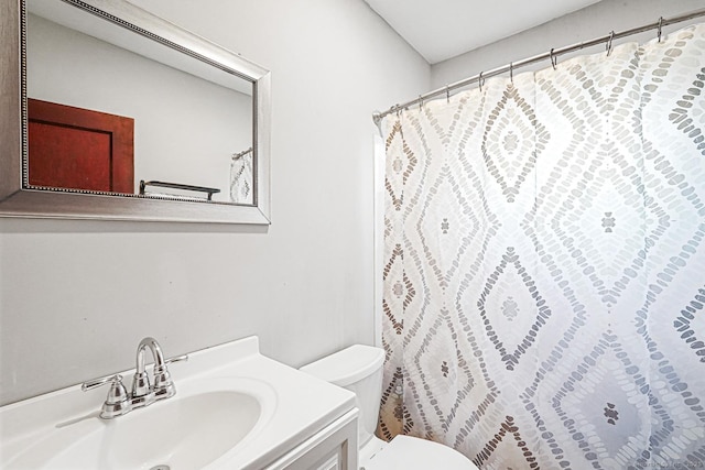 bathroom featuring toilet, vanity, and a shower with curtain