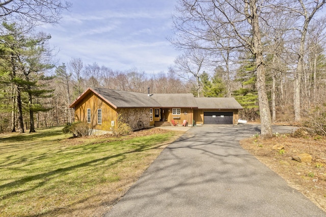 ranch-style home featuring a front lawn, a garage, and aphalt driveway