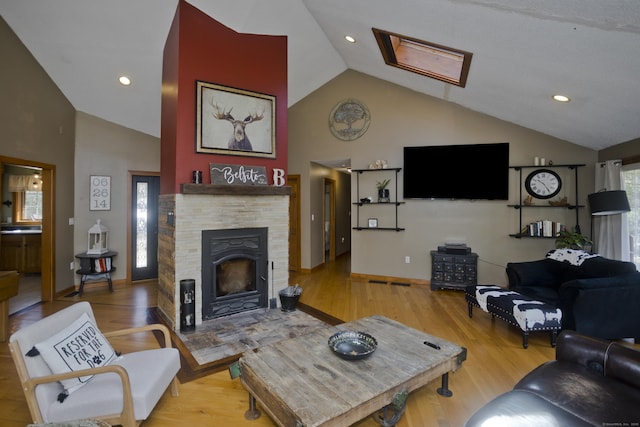 living room featuring wood finished floors, high vaulted ceiling, recessed lighting, baseboards, and a stone fireplace