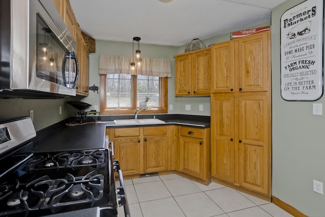 kitchen featuring a sink, brown cabinetry, stainless steel appliances, light tile patterned floors, and dark countertops