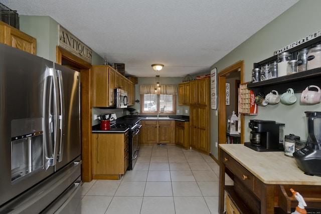 kitchen featuring a sink, stainless steel appliances, a textured ceiling, and light tile patterned floors