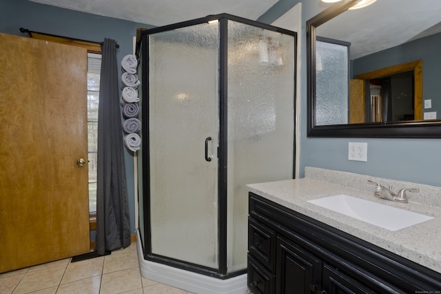 bathroom with tile patterned flooring, a shower stall, and vanity
