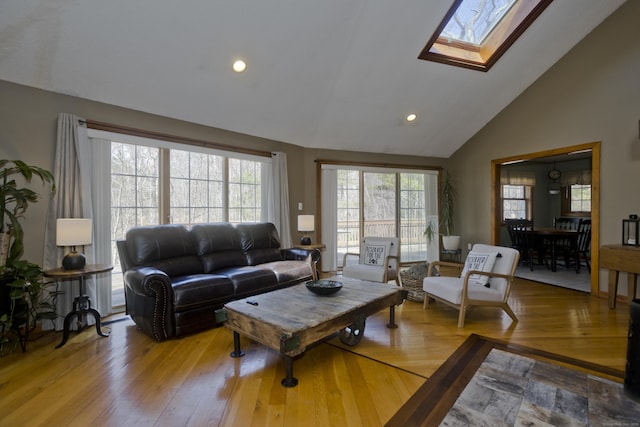 living room featuring light wood finished floors, recessed lighting, a skylight, and high vaulted ceiling