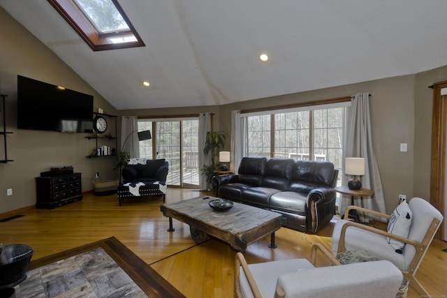 living room featuring visible vents, wood finished floors, and vaulted ceiling with skylight
