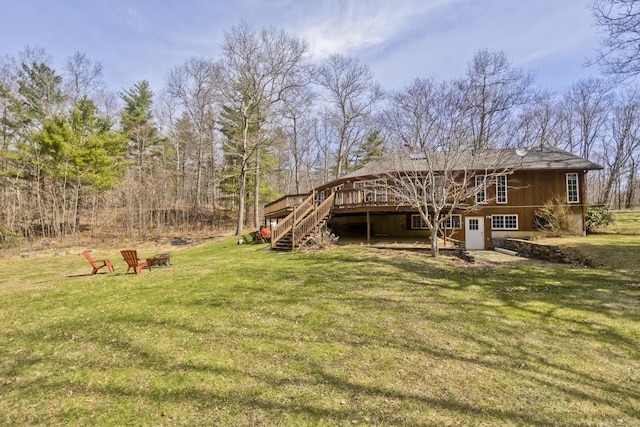 back of property with stairway, an outdoor fire pit, a deck, and a lawn