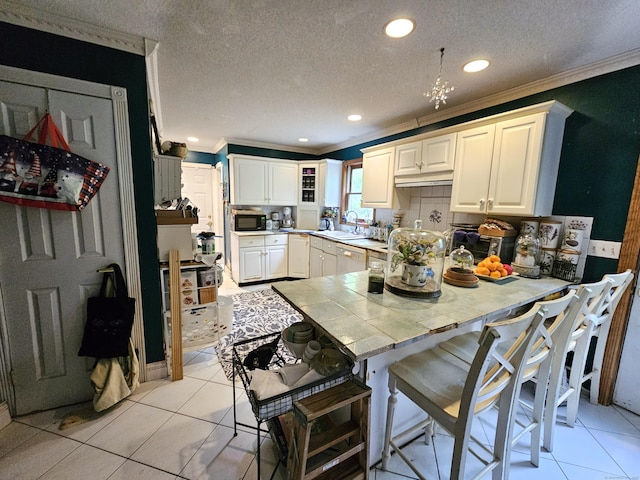 935 Gaylord Mountain Rd, Hamden, CT 06518 - kitchen with crown molding, a sink, a peninsula, black microwave, and tile counters