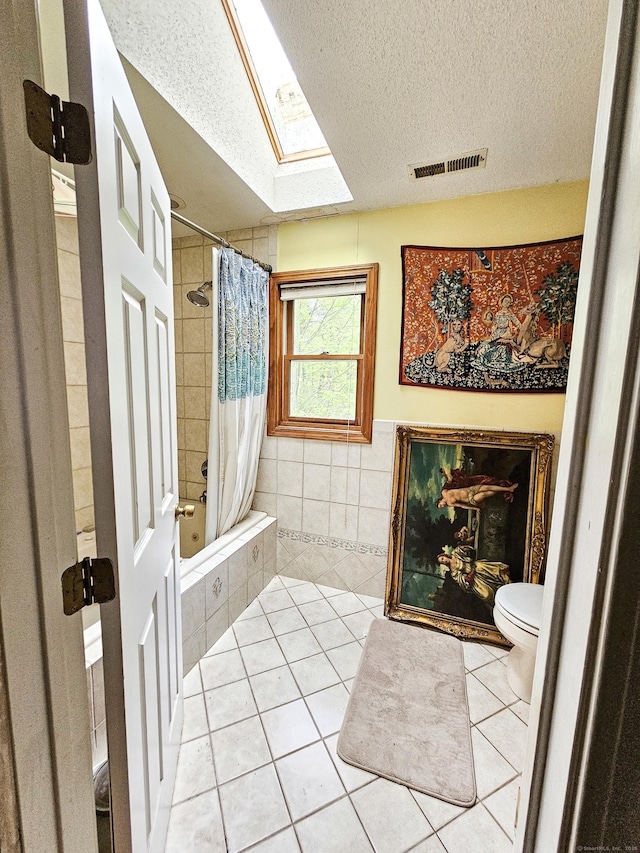 935 Gaylord Mountain Rd, Hamden, CT 06518 - bathroom featuring a textured ceiling, tile patterned floors, tiled shower / bath combo, tile walls, and a skylight