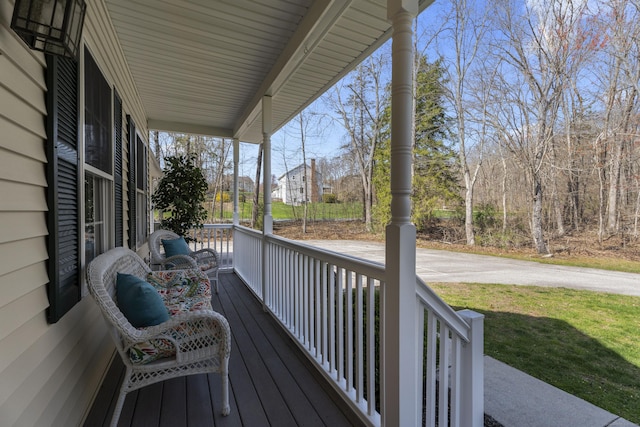 wooden deck featuring a porch and a lawn