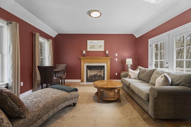 living area featuring baseboards, wood finished floors, and a fireplace with flush hearth