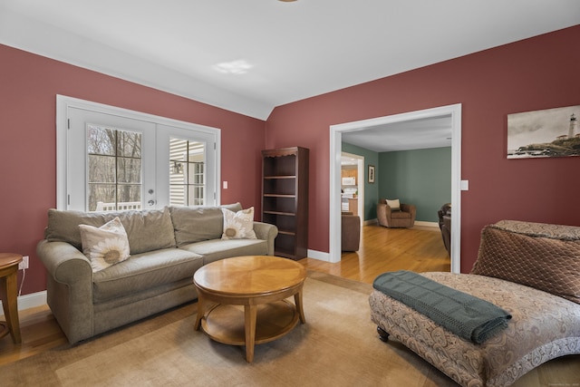 living room featuring baseboards, french doors, and light wood-style flooring