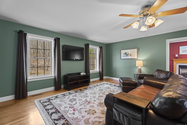 living room featuring baseboards, visible vents, wood finished floors, and a ceiling fan