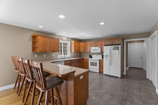 kitchen featuring recessed lighting, white appliances, a sink, baseboards, and a peninsula