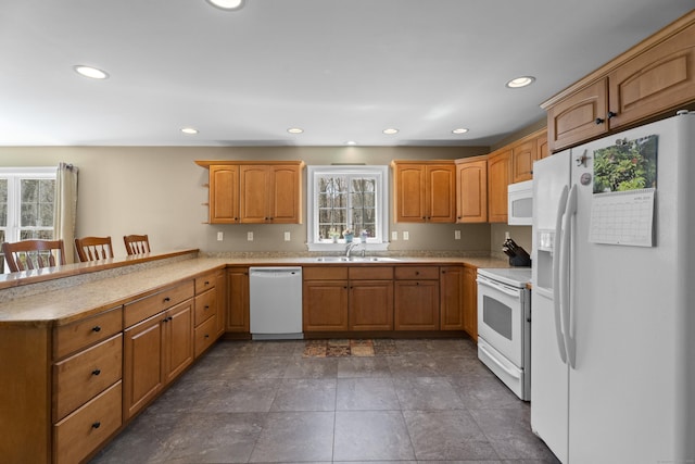 kitchen with a healthy amount of sunlight, white appliances, a peninsula, and a sink