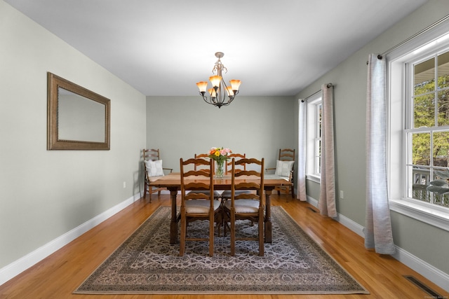 dining area with a chandelier, visible vents, light wood-style flooring, and baseboards