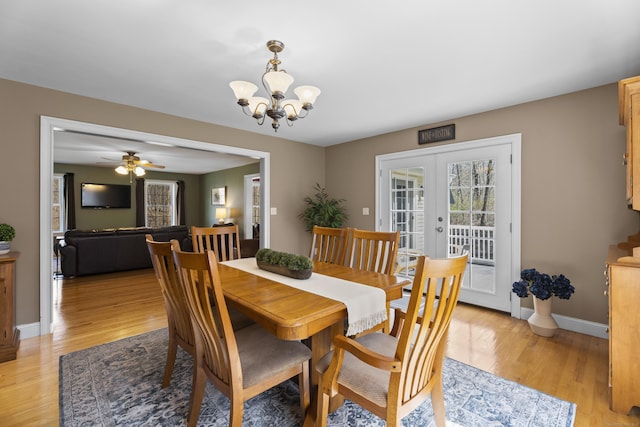 dining room featuring baseboards, ceiling fan with notable chandelier, light wood-style floors, and french doors