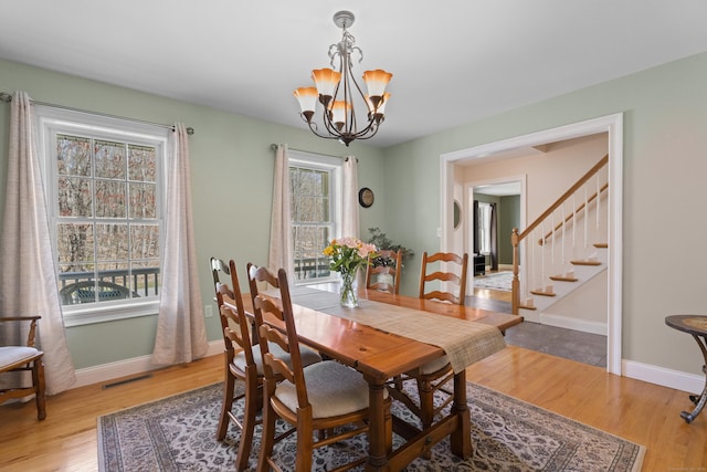 dining space featuring an inviting chandelier, stairway, wood finished floors, and visible vents
