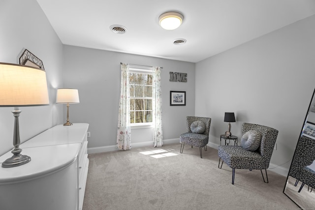 sitting room featuring visible vents, baseboards, and light carpet