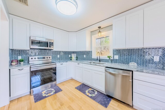 106 Lorraine Ter, Middletown, CT 06457 - kitchen featuring light stone counters, decorative backsplash, a sink, stainless steel appliances, and light wood-type flooring