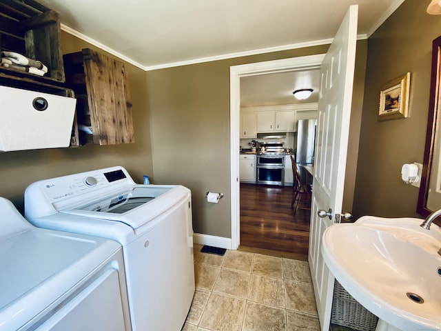 laundry room with a sink, ornamental molding, laundry area, and independent washer and dryer