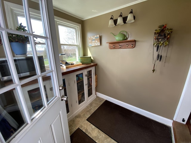 doorway to outside with baseboards and ornamental molding
