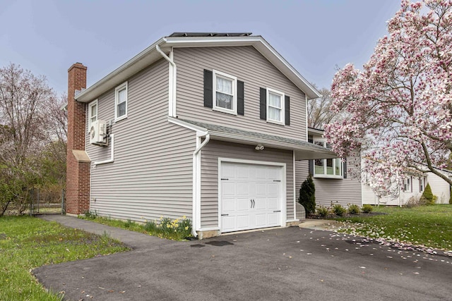 view of home's exterior featuring driveway, a chimney, cooling unit, and a garage