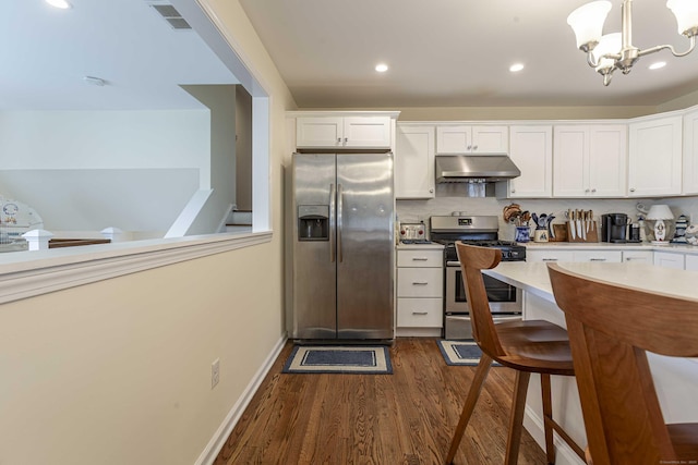 kitchen with dark wood-style floors, under cabinet range hood, stainless steel appliances, light countertops, and visible vents