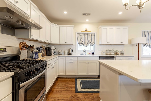 kitchen featuring under cabinet range hood, light countertops, visible vents, a sink, and gas range