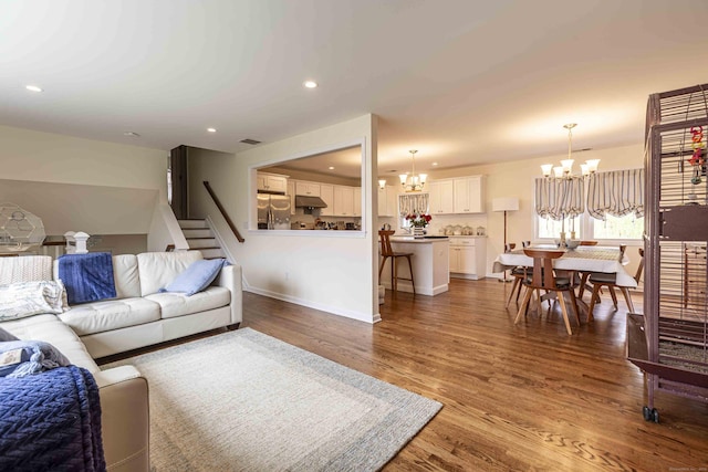 living room with stairway, a chandelier, visible vents, baseboards, and wood finished floors