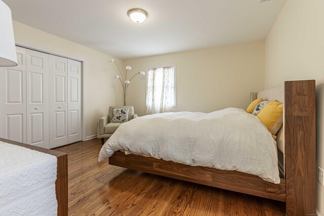 bedroom featuring wood finished floors, baseboards, and a closet
