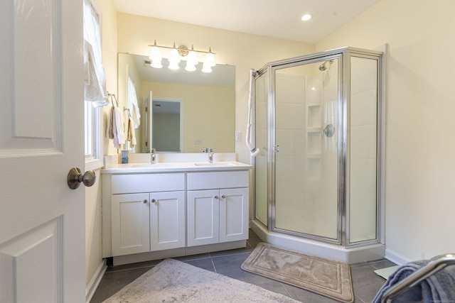 bathroom featuring double vanity, a shower stall, and a sink