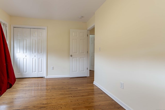 unfurnished bedroom with wood finished floors, a closet, and baseboards
