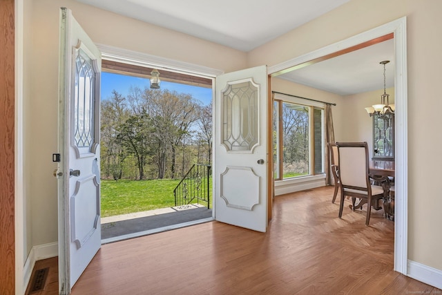 doorway featuring an inviting chandelier, baseboards, and visible vents