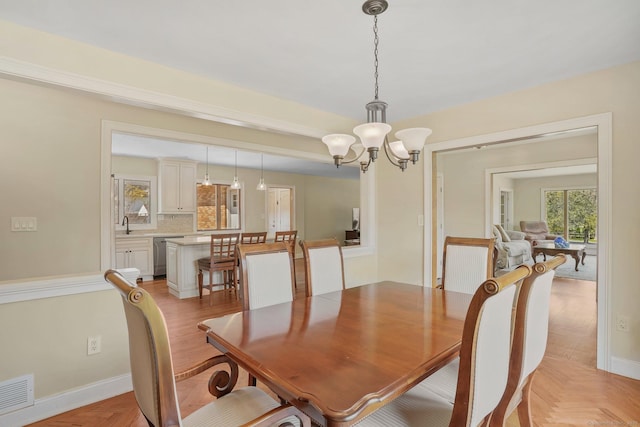 dining space with baseboards, visible vents, and a notable chandelier