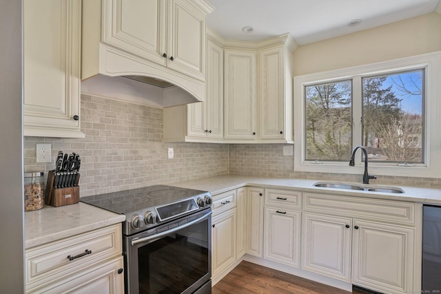 kitchen with a sink, tasteful backsplash, stainless steel range with electric cooktop, cream cabinets, and dishwasher