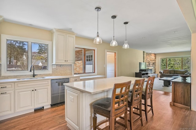 kitchen featuring a sink, a breakfast bar, dishwasher, and light wood-type flooring